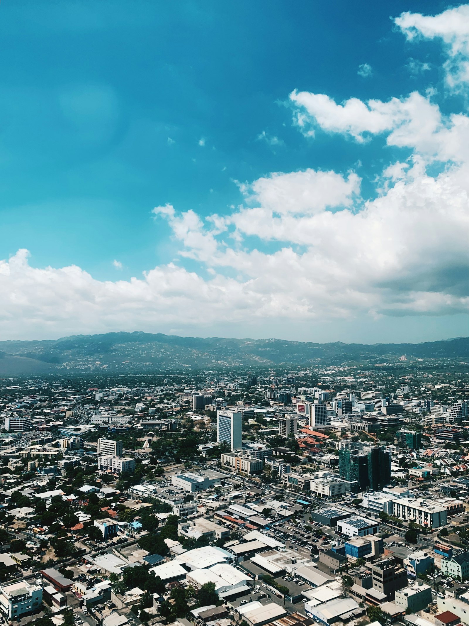 Aerial view of Kingston, Jamaica's cityscape with mountains in the background