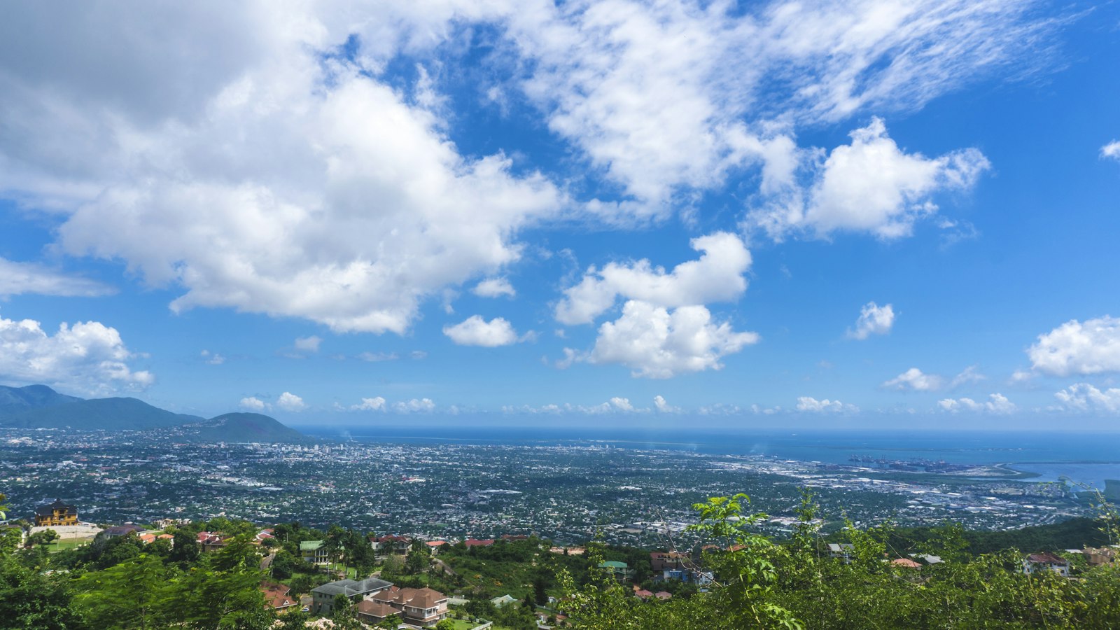 View over Kingston, Jamaica, from the hills above Red Hills Road, with the harbour and blue sea beyond the city