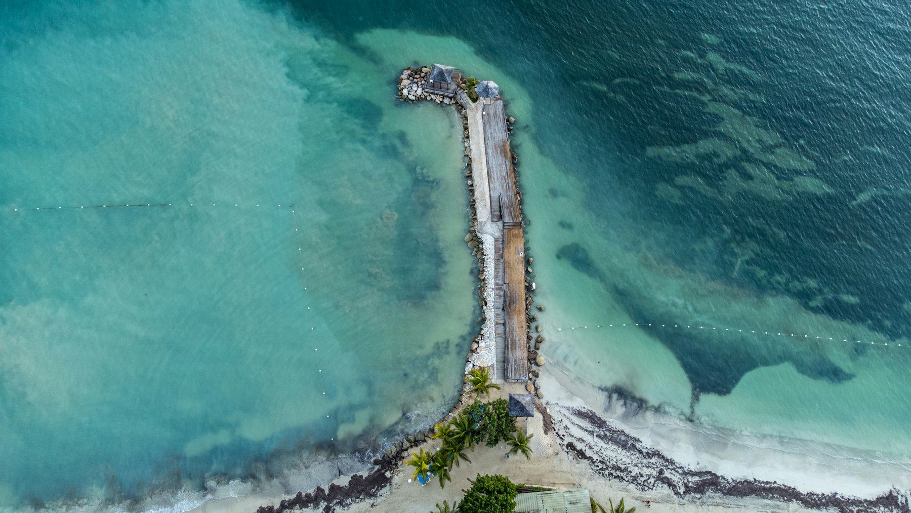 Aerial view of a wooden pier and gazebo extending into turquoise water off Montego Bay, Jamaica